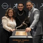 
              Alabama quarterback Bryce Young, center, poses for a photograph with his mom Julie, left, and father Craig, right, after winning the Heisman Trophy, Saturday, Dec. 11, 2021, in New York. (AP Photo/John Minchillo)
            