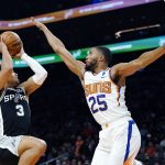 
              San Antonio Spurs forward Keldon Johnson (3) drives past Phoenix Suns forward Mikal Bridges (25) during the first half of an NBA basketball game Monday, Dec. 6, 2021, in Phoenix. (AP Photo/Ross D. Franklin)
            