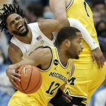 
              North Carolina guard R.J. Davis collides with Michigan center Hunter Dickinson (1) while guard DeVante' Jones (12) dribbles during the first half of an NCAA college basketball game in Chapel Hill, N.C., Wednesday, Dec. 1, 2021. (AP Photo/Gerry Broome)
            