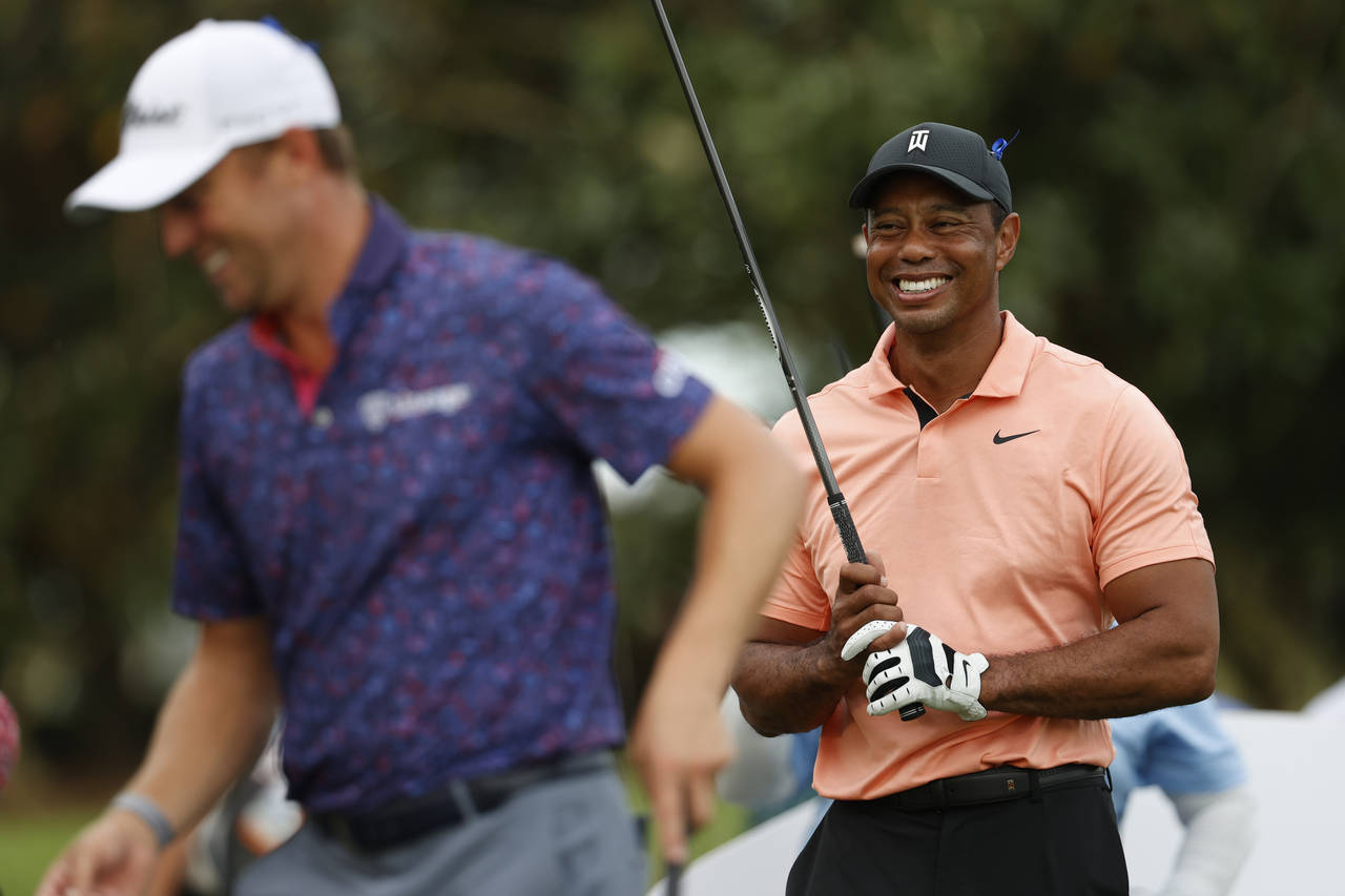 Tiger Woods, right, laughs with Justin Thomas on the 17th tee during the first round of the PNC Cha...