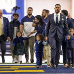 
              Marcus Freeman walks in surrounded by his family, captains and administration for a news conference Monday, Dec. 6, 2021 at the Irish Athletic Center in South Bend, Ind. Notre Dame formally introduced Freeman as its new football coach, a meteoric rise for the defensive coordinator. (Michael Caterina/South Bend Tribune via AP)
            