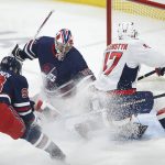 
              Winnipeg Jets goaltender Connor Hellebuyck (37) saves the shot from Washington Capitals' Beck Malenstyn (47) as Kristian Vesalainen (93) defends during the first period of an NHL hockey game Friday, Dec. 17, 2021 in Winnipeg, Manitoba. (John Woods/The Canadian Press via AP)
            
