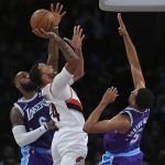 
              Portland Trail Blazers forward Norman Powell (24) shoots while being guarded by Los Angeles Lakers forward LeBron James (6) and guard Talen Horton-Tucker (5) during the first half of an NBA basketball game Friday Dec. 31, 2021, in Los Angeles. (AP Photo/John McCoy)
            