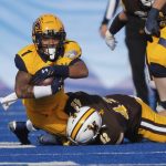 
              Kent State running back Marquez Cooper (1) stretches for an extra yard as he is tackled by Wyoming safety Isaac White (42) during the first half of the Idaho Potato Bowl NCAA college football game, Tuesday, Dec. 21, 2021, in Boise, Idaho. (AP Photo/Steve Conner)
            