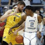 
              North Carolina guard Caleb Love (2) and Michigan center Hunter Dickinson (1) reach for the ball during the first half of an NCAA college basketball game in Chapel Hill, N.C., Wednesday, Dec. 1, 2021. (AP Photo/Gerry Broome)
            