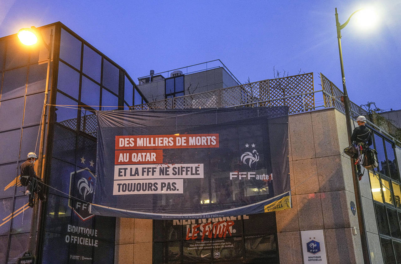Amnesty International activists unfurl a banner on the building of the French soccer federation hea...