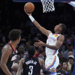 
              Oklahoma City Thunder guard Shai Gilgeous-Alexander, right, shoots in front of Houston Rockets forward Jae'Sean Tate, left, and guard Kevin Porter Jr. (3) during the first half of an NBA basketball game Wednesday, Dec. 1, 2021, in Oklahoma City. (AP Photo/Sue Ogrocki)
            