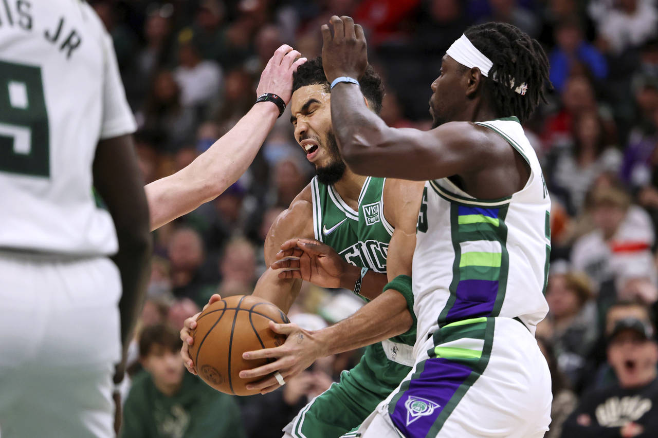 Boston Celtics forward Jayson Tatum (0) controls the ball while defended by Milwaukee Bucks guard J...