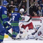 
              Vancouver Canucks' Vasily Podkolzin, back left, of Russia, scores the tying goal against Columbus Blue Jackets goalie Elvis Merzlikins, of Latvia, during the third period of an NHL hockey game Tuesday, Dec. 14, 2021 in Vancouver, British Columbia. (Darryl Dyck/The Canadian Press via AP)
            