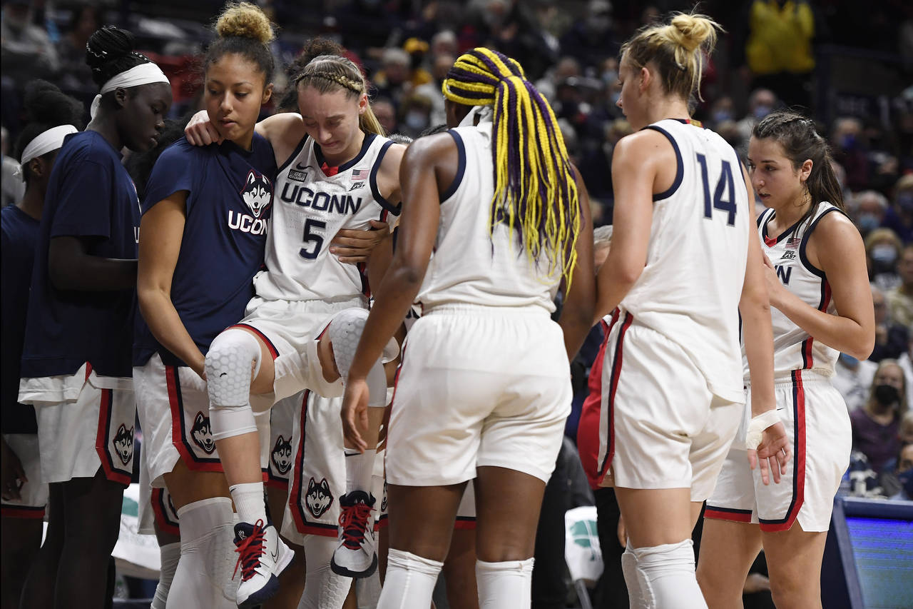 Connecticut's Paige Bueckers (5) is helped off the court by Amari DeBerrym, left, after injuring he...