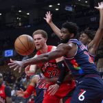 
              Toronto Raptors' Malachi Flynn, left, passes the ball past Philadelphia 76ers' Joel Embiid during the first half of an NBA basketball game Tuesday, Dec. 28, 2021, in Toronto. (Chris Young/The Canadian Press via AP)
            