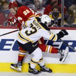 
              Calgary Flames' Trevor Lewis, left, takes a hit from Boston Bruins' Charlie McAvoy during the first period of an NHL hockey game Saturday, Dec. 11, 2021, in Calgary, Alberta. (Larry MacDougal/The Canadian Press via AP)
            