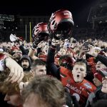 
              Cincinnati fans and players celebrate after winning the American Athletic Conference championship NCAA college football game against Houston Saturday, Dec. 4, 2021, in Cincinnati. (AP Photo/Jeff Dean)
            