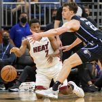 
              Miami Heat guard Kyle Lowry, left, passes the ball around Orlando Magic forward Franz Wagner (22) after he slipped on the court during the second half of an NBA basketball game, Friday, Dec. 17, 2021, in Orlando, Fla. (AP Photo/John Raoux)
            