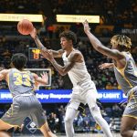 
              West Virginia forward Jalen Bridges (11) makes a pass while being guarded by Kent State guard Jeremiah Hernandez (33) during the first half of an NCAA college basketball game in Morgantown, W.Va., Sunday, Dec. 12, 2021. (AP Photo/William Wotring)
            