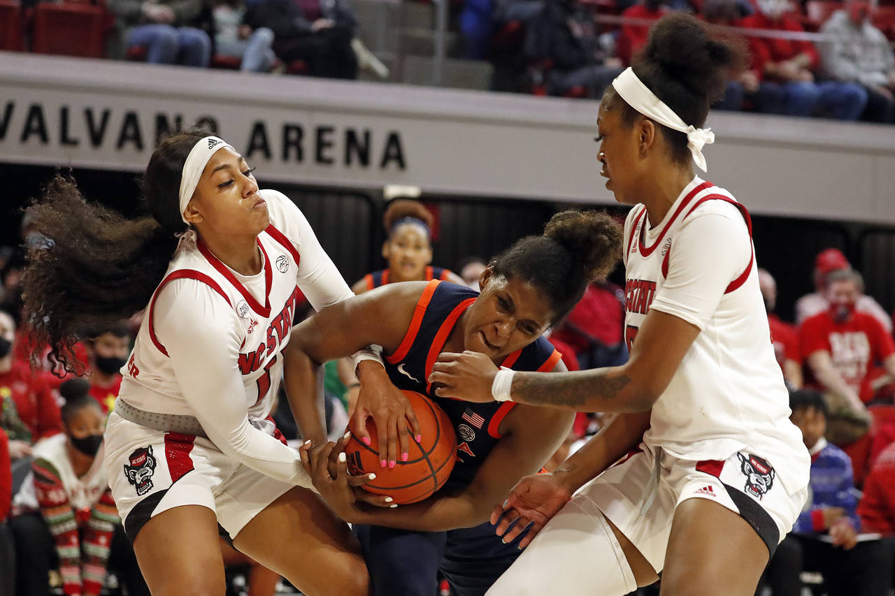 Virginia's Eleah Parker, center, tries to control the ball between North Carolina State's Jakia Bro...