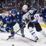 
              Vancouver Canucks' Bo Horvat (53) checks Winnipeg Jets' Mark Scheifele (55) during the first period of an NHL hockey game Friday, Dec. 10, 2021, in Vancouver, British Columbia. (Darryl Dyck/The Canadian Press via AP)
            