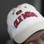 
              James Meredith, who integrated the University of Mississippi as its first Black student in 1962, wears a hat with a Mississippi state flag pin and one of the school's logos at his home in Jackson, Miss., Thursday, Oct. 28, 2021.  A person close to Meredith is selling “New Miss” merchandise and trying to trademark a logo with cursive script that is nearly identical to the university's Ole Miss logo. The university is fighting the trademark effort.  (AP Photo/Rogelio V. Solis)
            