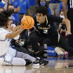 
              UCLA guard Tyger Campbell, left, passes the ball from the floor while defended by Colorado guard KJ Simpson (2) during the first half of an NCAA college basketball game in Los Angeles, Wednesday, Dec. 1, 2021. (AP Photo/Ashley Landis)
            
