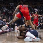 
              Philadelphia 76ers' Joel Embiid protects himself as Toronto Raptors' Gary Trent Jr. steps over him during the first half of an NBA basketball game Tuesday, Dec. 28, 2021, in Toronto. (Chris Young/The Canadian Press via AP)
            