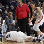 
              Connecticut's Paige Bueckers stumbles injured as Connecticut's Nika Mühl and head coach Geno Auriemma looks on the second half of an NCAA college basketball game against Notre Dame, Sunday, Dec. 5, 2021, in Storrs, Conn. (AP Photo/Jessica Hill)
            