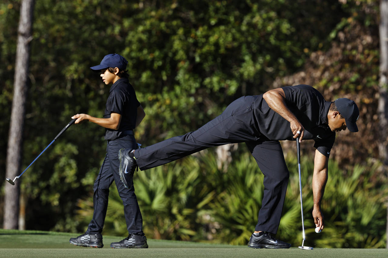 Tiger Woods, right, and his son Charlie finish putting on the second hole during the first round of...