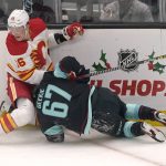 Calgary Flames defenseman Nikita Zadorov, left, looks for the puck as Seattle Kraken center Morgan Geekie hits the ice near the boards during the first period of an NHL hockey game Thursday, Dec. 30, 2021, in Seattle. (AP Photo/Ted S. Warren)