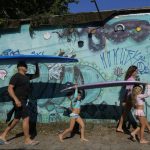 
              Eduardo Tanimoto, left, walks to the beach for a surf practice with daughter Rayana Tanimoto and five-year-old twin granddaughters Eloa, center, and Ayla, at Maresias beach, in Sao Sebastiao, Brazil, Saturday, Nov. 27, 2021. Tanimoto, 52, is a native of Sao Paulo's countryside, and he started coming to Sao Sebastiao to surf when the sport revolved around lifestyle rather than competition. (AP Photo/Andre Penner)
            