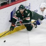 
              Minnesota Wild right wing Ryan Hartman (38) and Toronto Maple Leafs defenseman Rasmus Sandin (38) battle for the puck during the first period of an NHL hockey game, Saturday, Dec. 4, 2021, in St. Paul, Minn. (AP Photo/Andy Clayton-King)
            