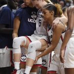 
              Connecticut's Paige Bueckers, center, is helped off the court by Amari DeBerry, left, and Evina Westbrook in the second half of an NCAA college basketball game against Notre Dame, Sunday, Dec. 5, 2021, in Storrs, Conn. (AP Photo/Jessica Hill)
            