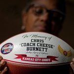 
              Carolyn Burnett holds a football presented as an award to her son by the Kansas City Chiefs, Monday, Dec. 13, 2021, in Olathe, Kan. Chris Burnett, an unvaccinated 34-year-old father who coached football at Olathe East High School, died in September as a result of COVID-19 after nearly two weeks on a ventilator. ​For its Christmas card photo, the Burnett family ultimately opted to hold up a football presented as a memorial by the Kansas City Chiefs to represent Chris. (AP Photo/Charlie Riedel)
            