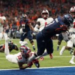 
              UTSA running back Sincere McCormick (3) leaps through the hands of Western Kentucky defensive back Miguel Edwards (13) for a touchdown during the second half of an NCAA college football game for the Conference USA championship Friday, Dec. 3, 2021, in San Antonio. (AP Photo/Eric Gay)
            