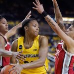 
              Michigan forward Naz Hillmon (00) passes the ball as Ohio State guard Taylor Thierry, left, and, guard Rikki Harris defend during the second half of an NCAA college basketball game, Friday, Dec. 31, 2021, in Ann Arbor, Mich. (AP Photo/Carlos Osorio)
            