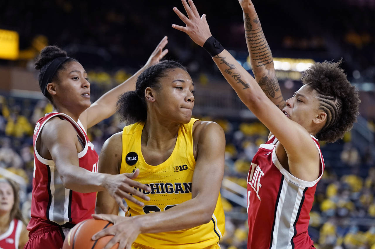 Michigan forward Naz Hillmon (00) passes the ball as Ohio State guard Taylor Thierry, left, and, gu...