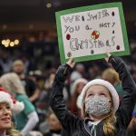 
              A young fan holds up a Christmas-themed sign during the first half of an NBA basketball game between the Milwaukee Bucks and the Boston Celtics, Saturday, Dec. 25, 2021, in Milwaukee. (AP Photo/Jon Durr)
            