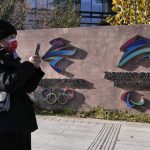 
              A visitor to the Shougang Park walks past the logos for the Beijing Winter Olympics and Paralympics in Beijing, China, Tuesday, Nov. 9, 2021. China on Monday, Dec. 6, 2021 threatened to take "firm countermeasures" if the U.S. proceeds with a diplomatic boycott of February's Beijing Winter Olympic Games. (AP Photo/Ng Han Guan)
            