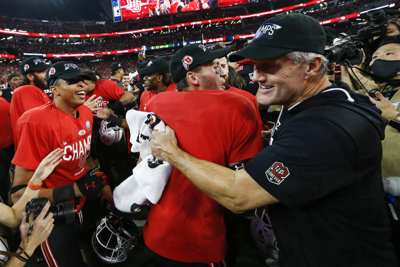 Utah coach Kyle Whittingham, right, celebrates with  team after Utah defeated Oregon 38-10 to win t...