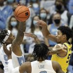 
              Michigan guard Eli Brooks (55) passes while North Carolina forward Armando Bacot (5) and guard Caleb Love defend during the first half of an NCAA college basketball game in Chapel Hill, N.C., Wednesday, Dec. 1, 2021. (AP Photo/Gerry Broome)
            