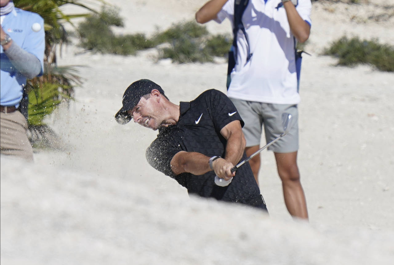 Rory McIlroy, of Northern Ireland, hits out of a bunker on the 5th hole during the first round of t...