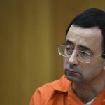 
              FILE - Larry Nassar listens as Rachael Denhollander gives her victim impact statement, Feb. 2, 2018, in Eaton County Circuit Court in Charlotte, Mich. The legal wrangling between USA Gymnastics and the victims of sexual abuse by Nassar, among others, is over. A federal bankruptcy court in Indianapolis on Monday, Dec. 13, 2021, confirmed a $380 million settlement between USA Gymnastics and the U.S. Olympic and Paralympic Committee and the hundreds of victims, ending one aspect of the fallout of the largest sexual abuse scandal in the history of the U.S. Olympic movement. (Matthew Dae Smith/Lansing State Journal via AP, File)
            
