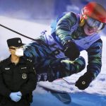 
              FILE - A police officer wearing a face mask and goggles to protect against COVID-19, stands near a poster of a skier on the wall at a train station in Zhangjiakou in northern China's Hebei Province, Friday, Nov. 26, 2021. China is threatening to take “firm countermeasures" if the U.S. proceeds with a diplomatic boycott of February's Beijing Winter Olympic Games. Foreign Ministry spokesperson Zhao Lijian on Monday accused U.S. politicians of grandstanding over the issue of not sending dignitaries to attend the events that China hopes will showcase its economic development. (AP Photo/Mark Schiefelbein, File)
            