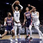 
              Memphis Grizzlies guard Ja Morant (12) drives to the basket between Brooklyn Nets forward Nic Claxton (33) and guard DeAndre' Bembry (95) during the first half of an NBA basketball game Monday, Jan. 3, 2022, in New York. (AP Photo/Adam Hunger)
            