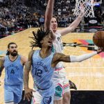 
              Memphis Grizzlies guard Ja Morant (12) drives to the basket against San Antonio Spurs center Jakob Poeltl (25) during the second half of an NBA basketball game, Wednesday, Jan. 26, 2022, in San Antonio. (AP Photo/Eric Gay)
            