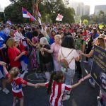 
              Supporters of Serbia's Novak Djokovic dance and sing outside the Park Hotel, used as an immigration detention hotel where Djokovic is confined in Melbourne, Australia, Sunday, Jan. 9, 2022. After four nights in hotel detention Novak Djokovic will get his day in court on Monday in a controversial immigration case that has polarized opinions in the tennis world and elicited heartfelt support for the star back home in his native Serbia. (AP Photo/Mark Baker)
            