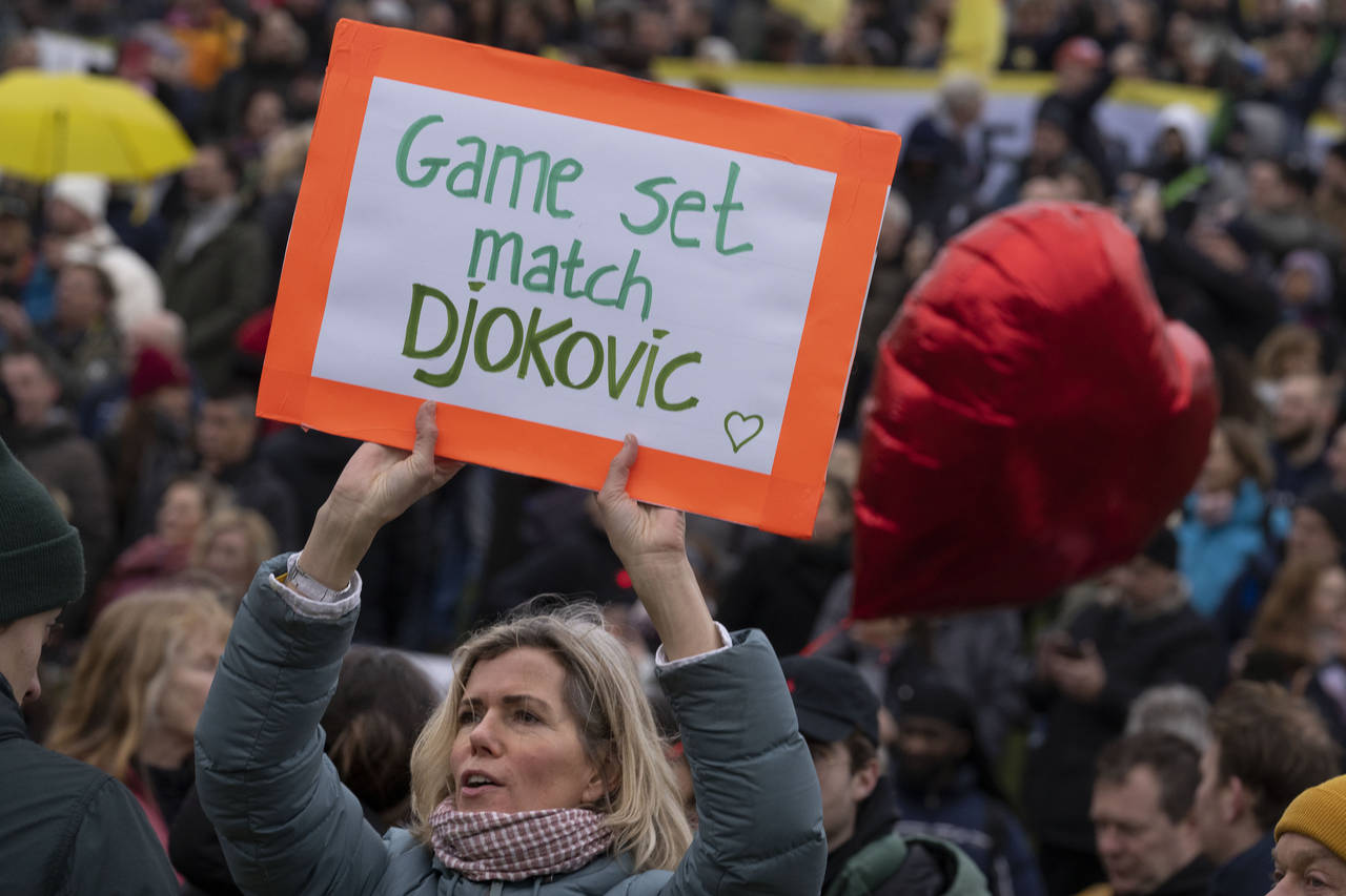 A woman holds a message for Serbia's Novak Djokovic as thousands of people protested against the Du...