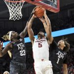 
              Arkansas guard Au'Diese Toney (5) has his shot blocked as he tries to drive past Texas A&M defenders Tyrece Radford (23) and Marcus Williams (1) during the first half of an NCAA college basketball game Saturday, Jan. 22, 2022, in Fayetteville, Ark. (AP Photo/Michael Woods)
            