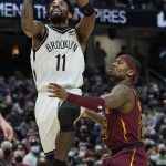 
              Brooklyn Nets' Kyrie Irving (11) drives against Cleveland Cavaliers' Brandon Goodwin (26) in the second half of an NBA basketball game, Monday, Jan. 17, 2022, in Cleveland. (AP Photo/Tony Dejak)
            