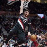 
              Portland Trail Blazers center Jusuf Nurkic, left, hangs on the rim after dunking in front of to Minnesota Timberwolves guard Jaylen Nowell during the first half of an NBA basketball game in Portland, Ore., Tuesday, Jan. 25, 2022. (AP Photo/Craig Mitchelldyer)
            