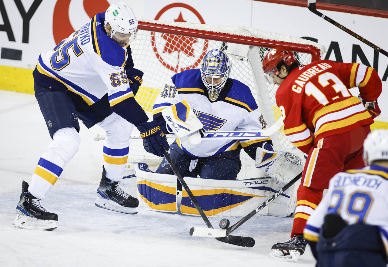 St. Louis Blues' Colton Parayko, left, and Calgary Flames' Johnny Gaudreau, right, battle for the p...