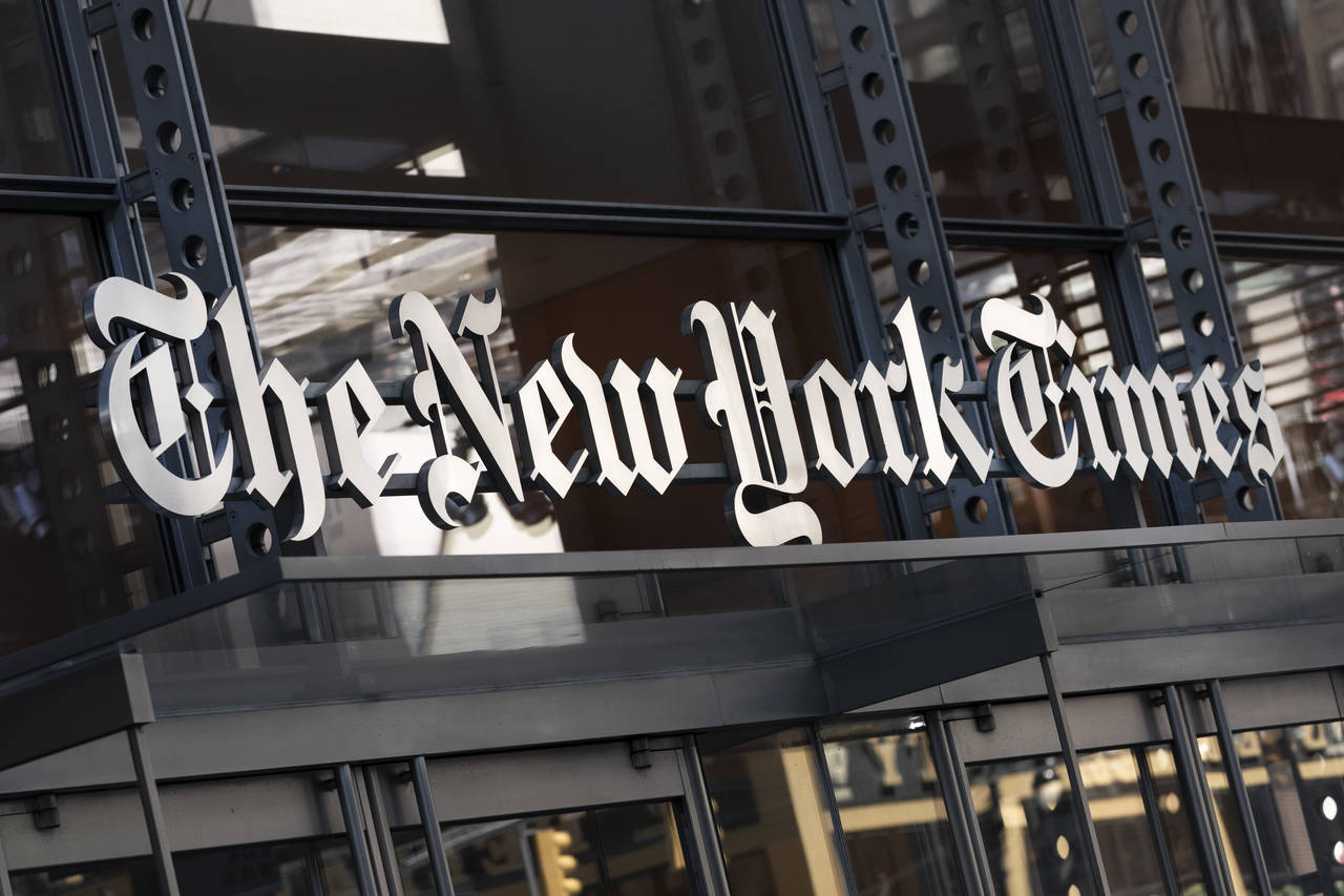 FILE - A sign for The New York Times hangs above the entrance to its building on May 6, 2021 in New...
